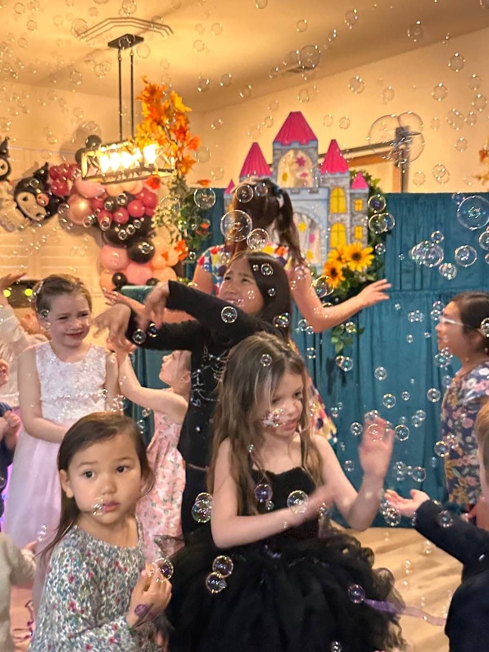 Excited children dance and play in a cloud of bubbles.