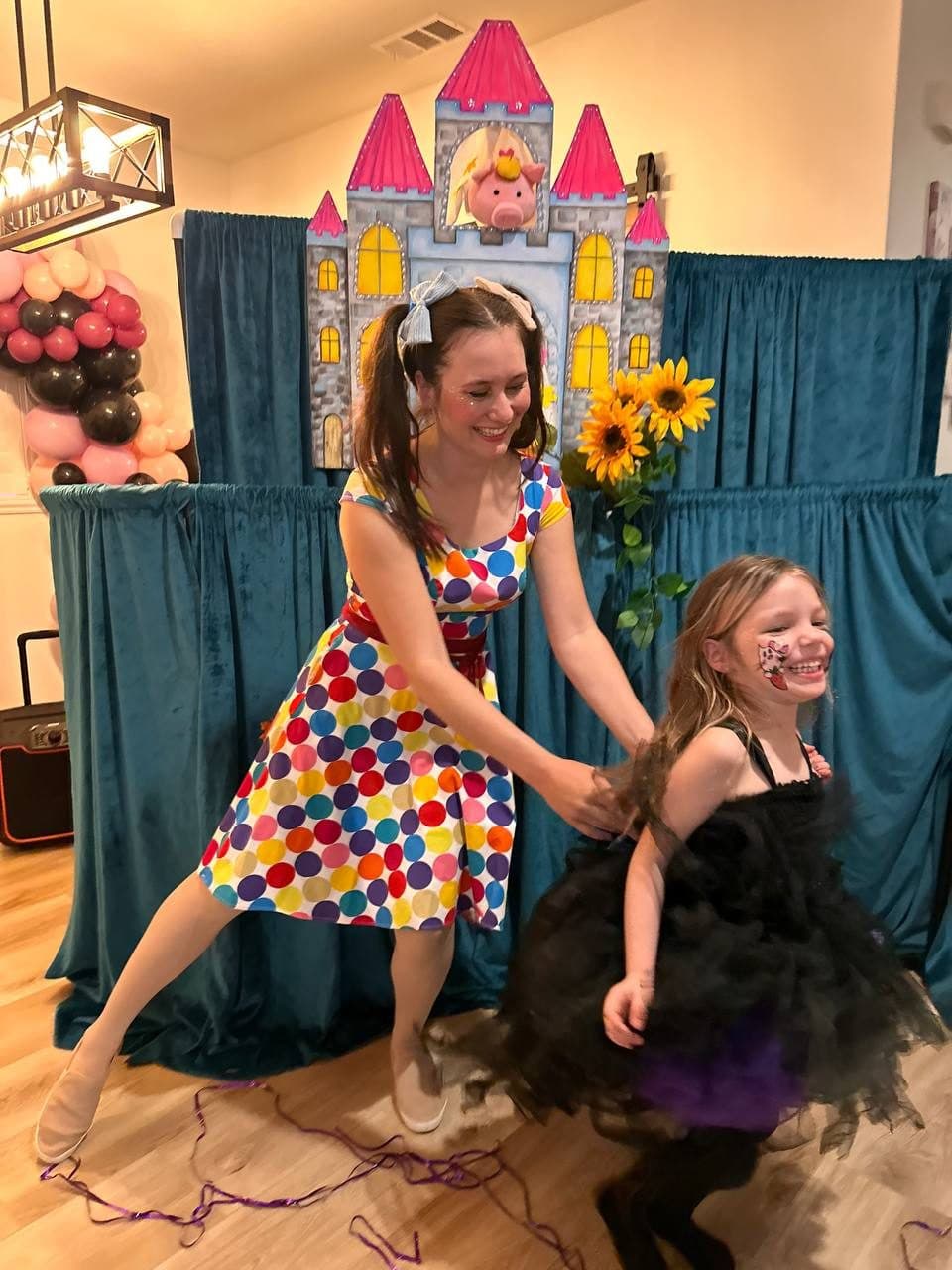 A performer spins and dances with a giggling girl at an indoor party.