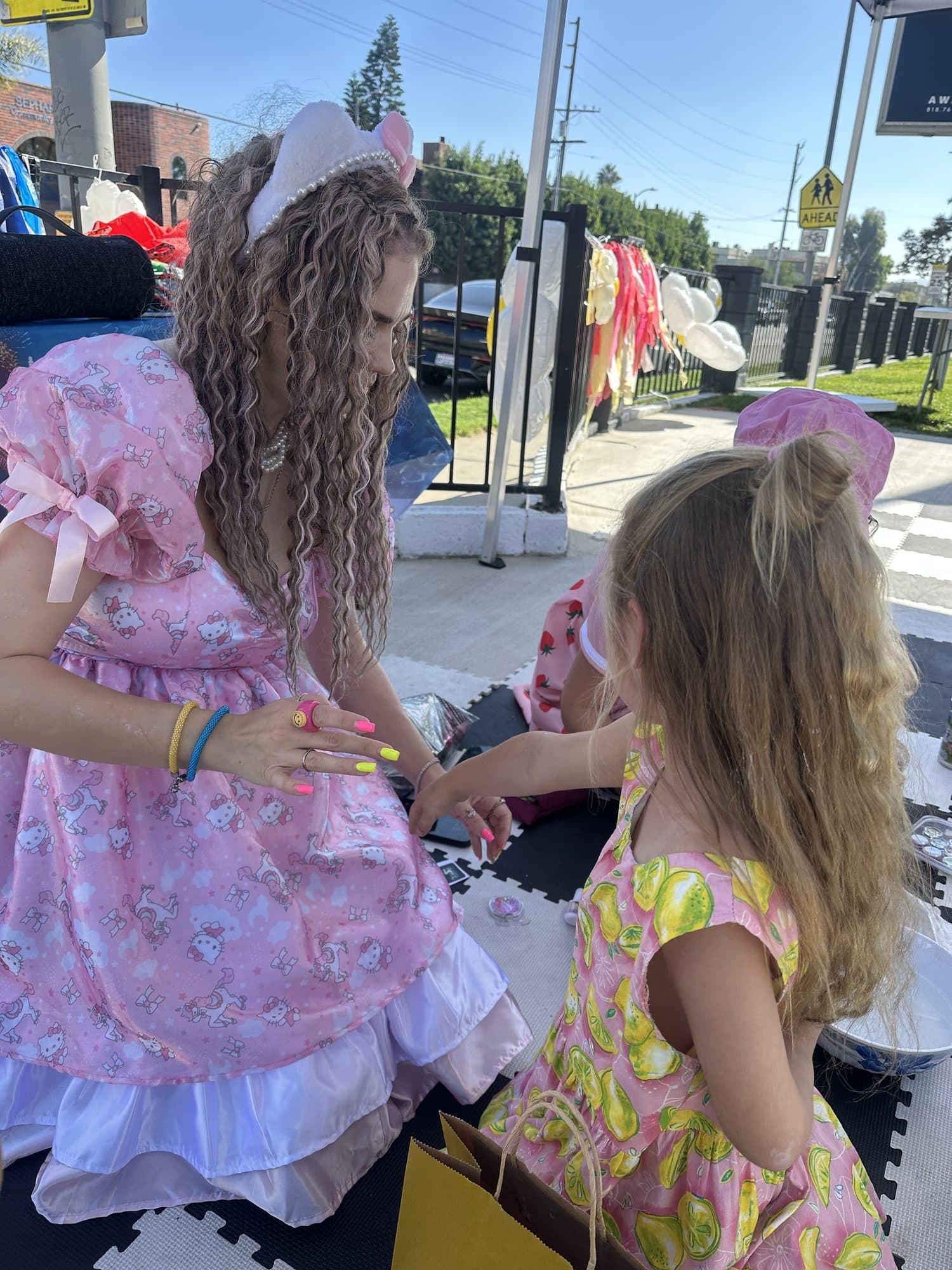 A costumed performer kneels to greet a delighted little girl at an outdoor event.