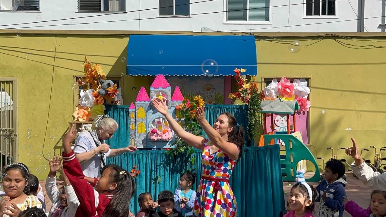 Children raise their hands cheering amid floating bubbles during the show.