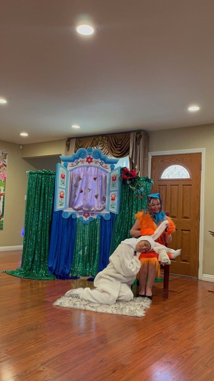Two costumed performers act out a tender scene on a decorated stage.