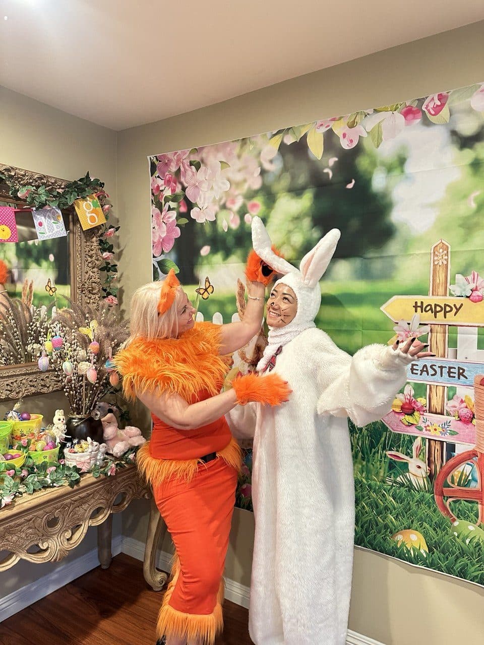 Two performers in fox and rabbit costumes pose together before a spring backdrop.