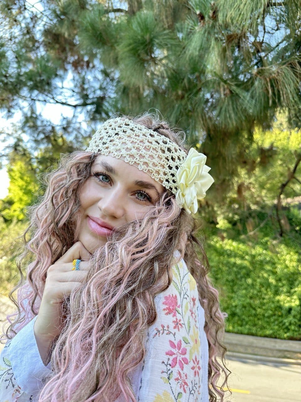 A warm close-up portrait of a smiling performer with a floral wrap.